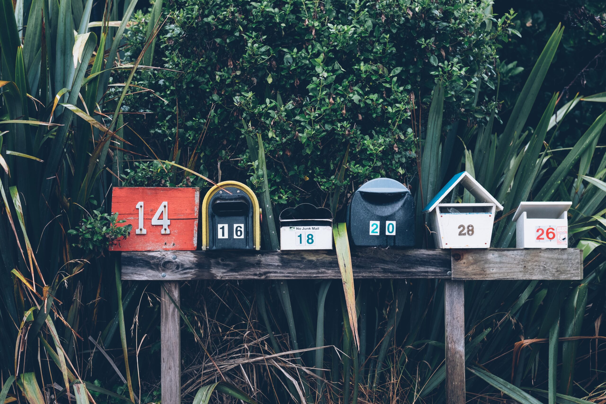 Different style mailboxes with plants and bushes behind them in Southeast Missouri