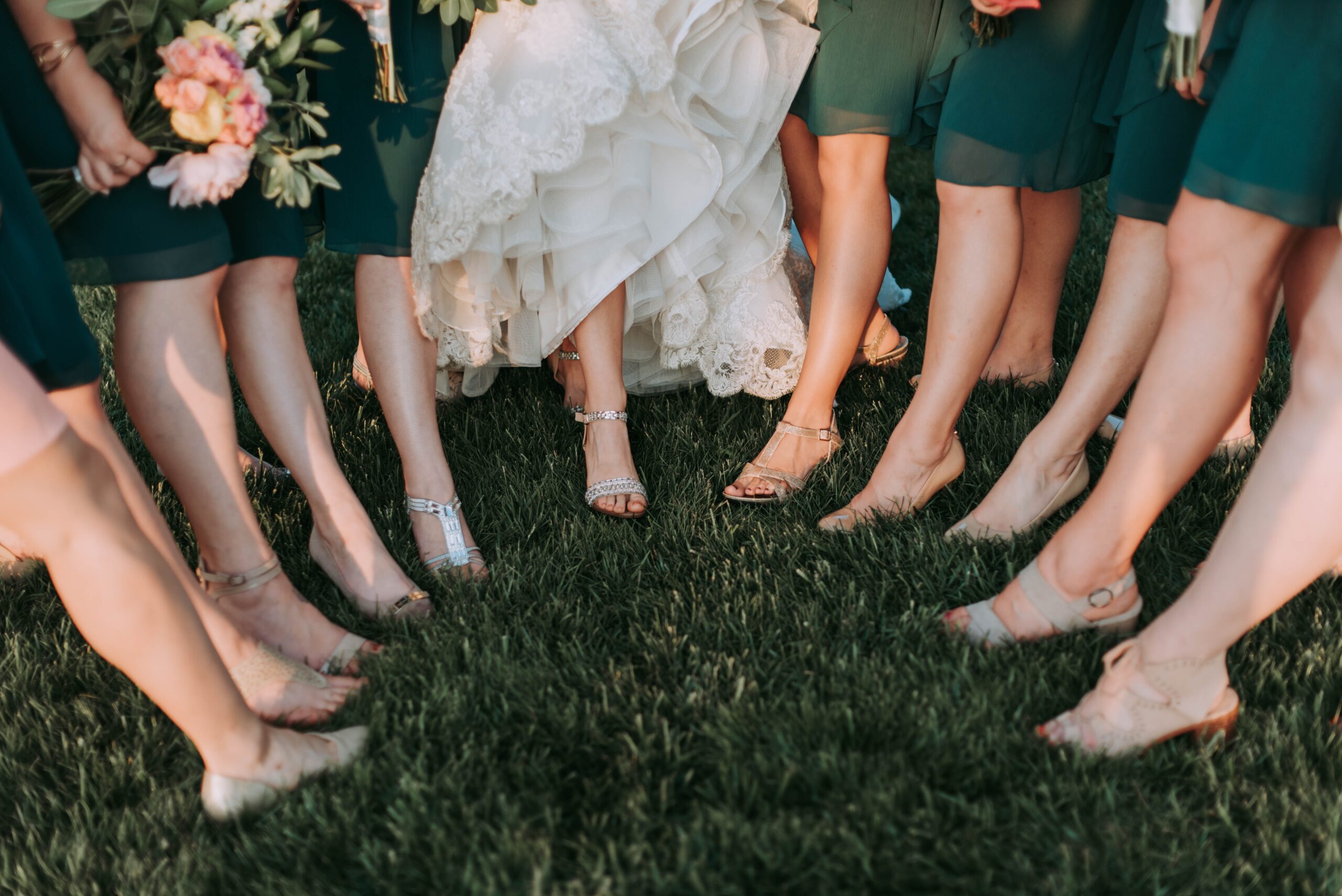 Bridal party putting one foot forward toward the middle for a picture of their feet.